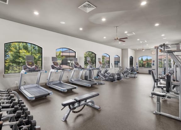 a gym with cardio equipment and windows