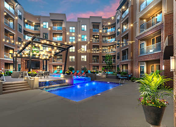 A large outdoor pool area with a hot tub and lounge chairs at a residential building.