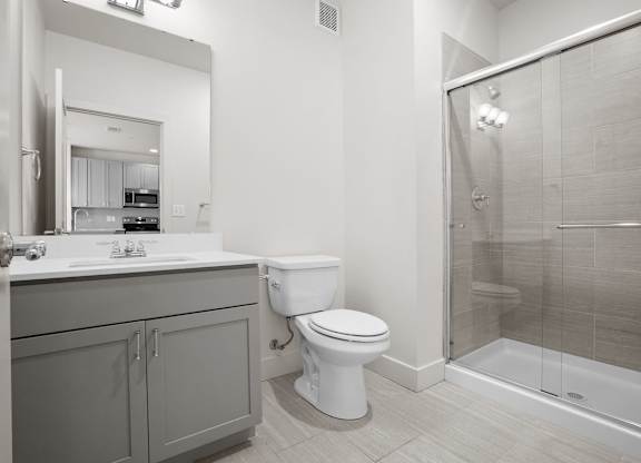 A large bathroom with modern finishes and a sliding glass door walk-in shower.