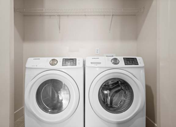 Included front-loading washer & dryer inside a laundry room with a wire rack shelf at The Mirabelle Luxury Apartments on the Plaza in Kansas City.