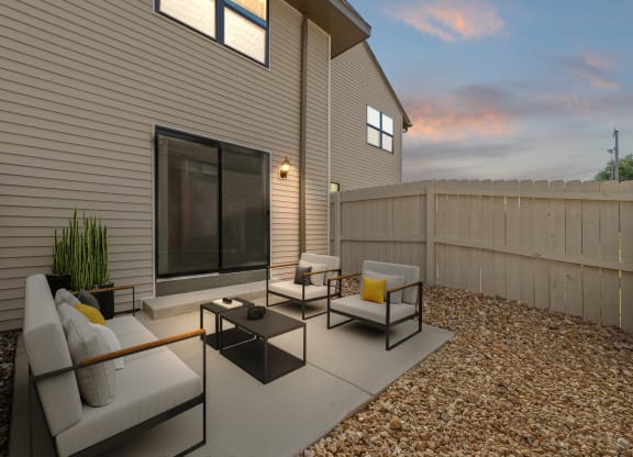 a patio with couches and chairs in front of a house