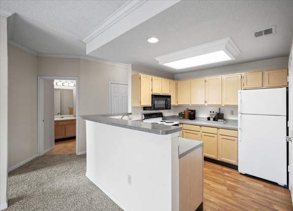 A kitchen with white appliances and wooden cabinets.at The Claremont Apartment Homes, Overland Park Kansas