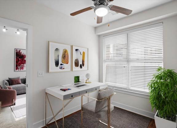 a home office with a ceiling fan and a large window
