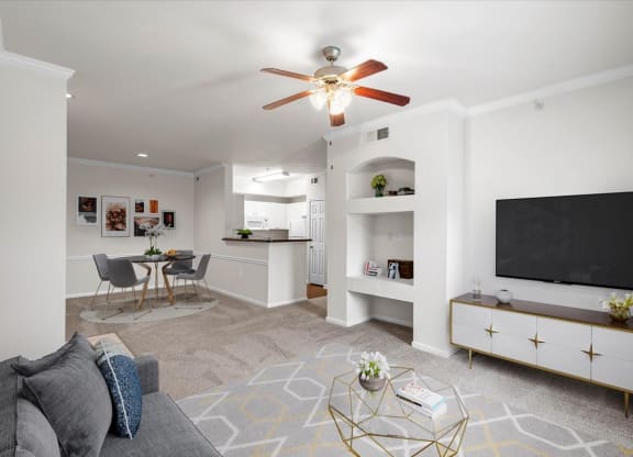 a living room with a ceiling fan and a flat screen tv