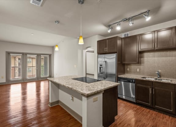 a kitchen with a large island with granite countertops and dark wood cabinets