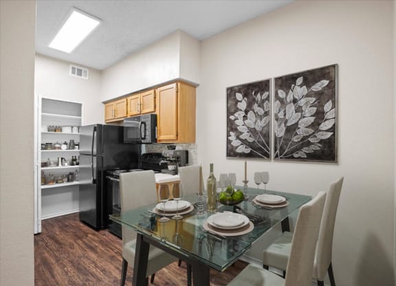 a dining area with a glass table and chairs and a kitchen in the background at Creekview Apartment Homes, Texas