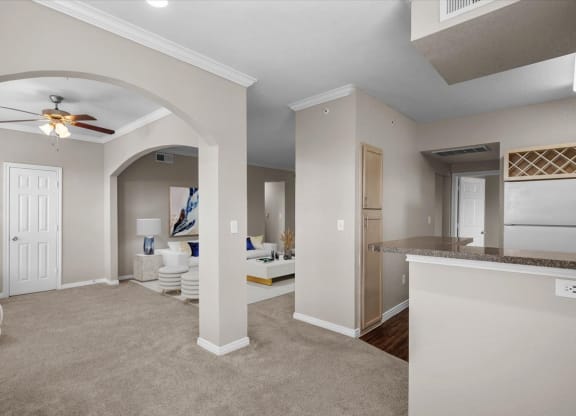 a living room and kitchen area with a ceiling fan at The Clairborne Apartment Homes, Grand Prairie