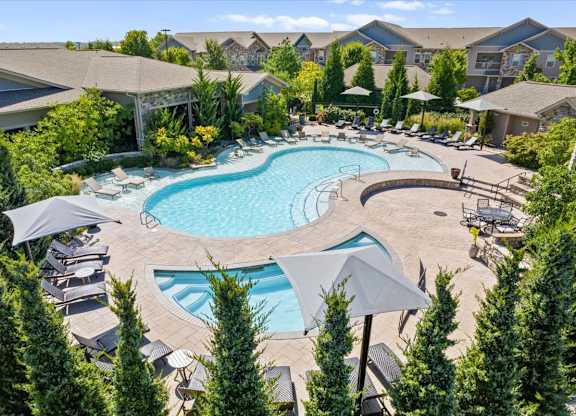 an aerial view of a resort style pool with chaise lounge chairs and umbrellas at Stonepost Crossing Apartments, Overland Park, Kansas