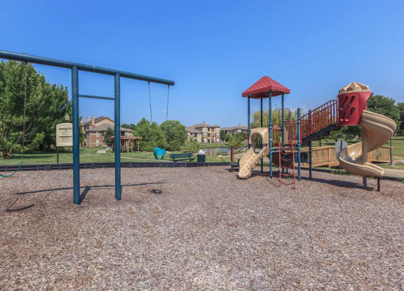 A playground with slides and swings at Stonepost Lakeside Apartments in Olathe, KS.
