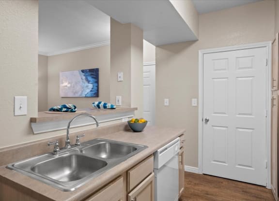 a kitchen with a sink and a dishwasher at The Clairborne Apartment Homes, Texas