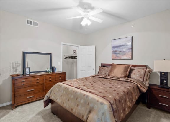 a bedroom with a bed and dresser at The Clairborne Apartment Homes, Grand Prairie