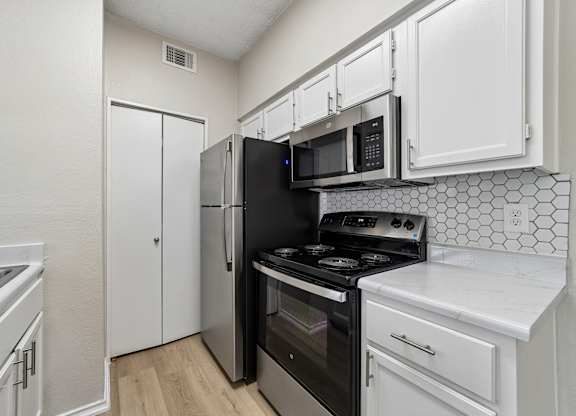 A kitchen with black appliances and white cabinets.