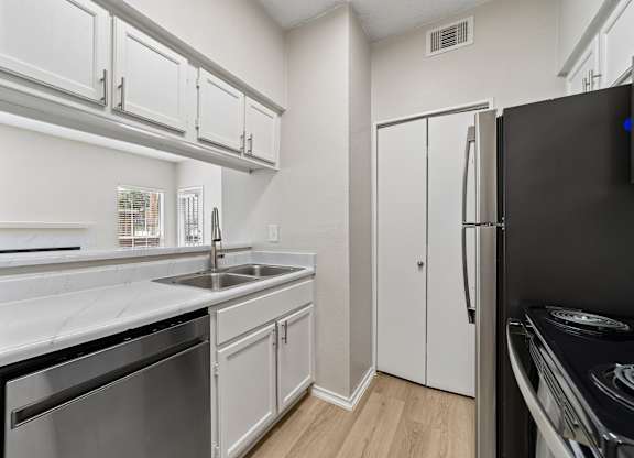 A modern kitchen with white cabinets and a black refrigerator.