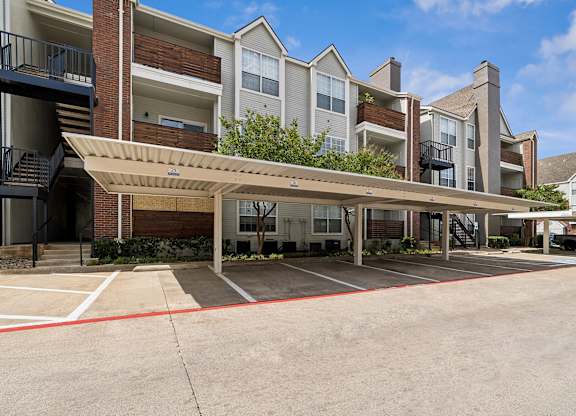 A large apartment complex with a parking lot in front.