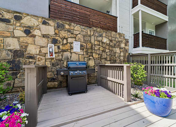 A stone wall with a grill and a planter with flowers.