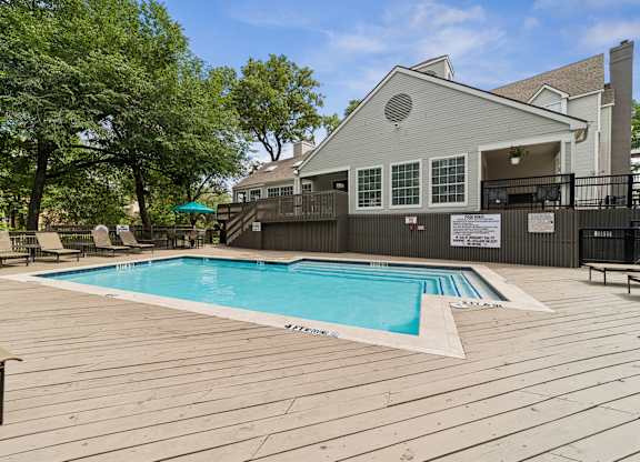 A pool with a deck and a house in the background.