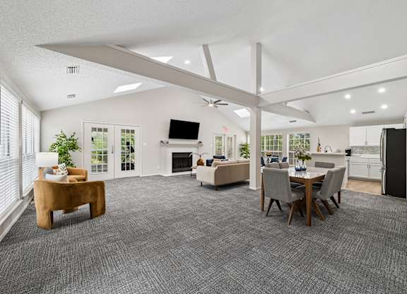 A spacious living room with a grey carpet and a television on the wall.
