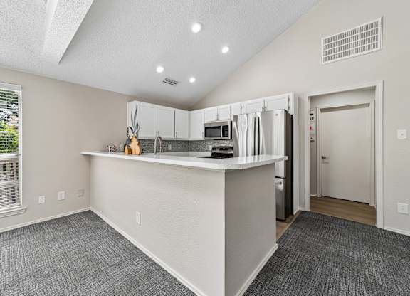 A kitchen with a white counter and a window with blinds.