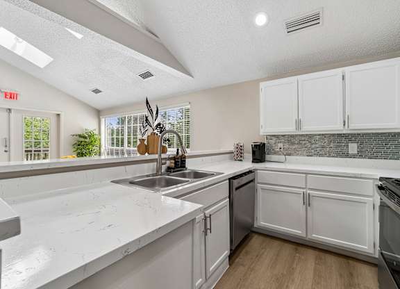 A kitchen with white cabinets and a marble countertop.