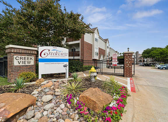 A sign for Creekview Apartment Homes is displayed in front of a gated entrance.