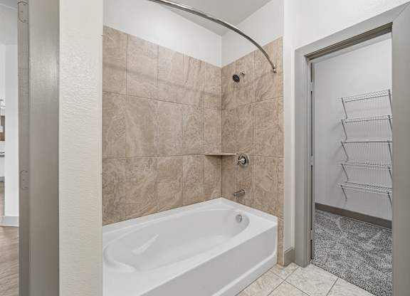 A bathroom with a tub and a walk in closet.