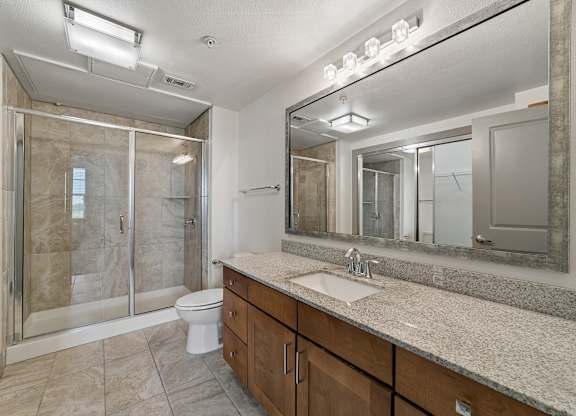 A bathroom with a sink, mirror, and shower.