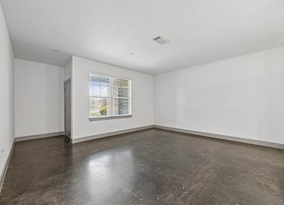 Empty room with a window and concrete floor.