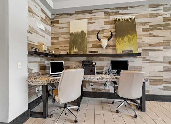 Two chairs are in front of a desk with a laptop and a monitor.