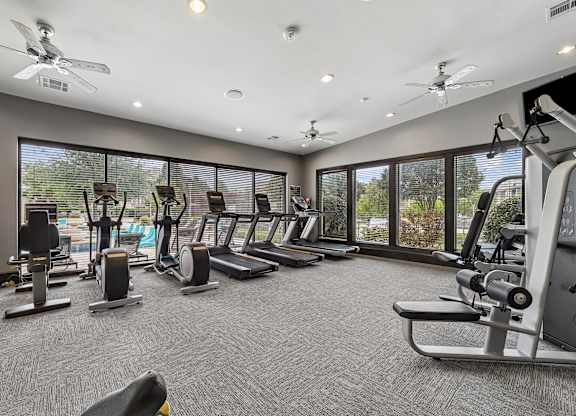 A spacious gym with various exercise equipment and a ceiling fan.