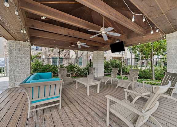 A wooden deck with chairs and a fan.