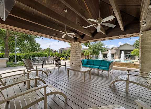 A wooden deck with a green couch and chairs.