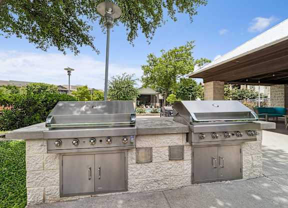 A stone outdoor kitchen with a grill and oven.