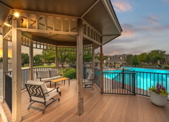 a poolside deck with chairs and a gazebo overlooking a swimming pool