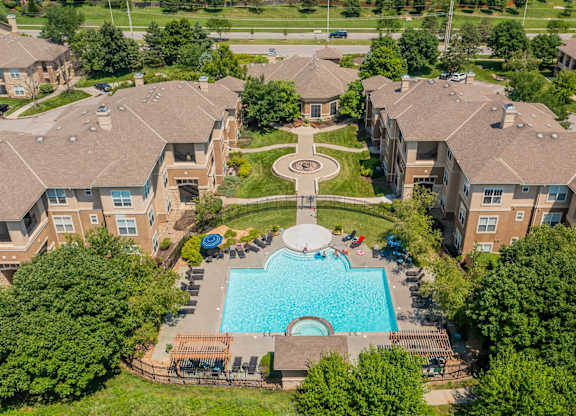 An aerial view of a swimming pool and courtyard surrounded by apartment buildings.