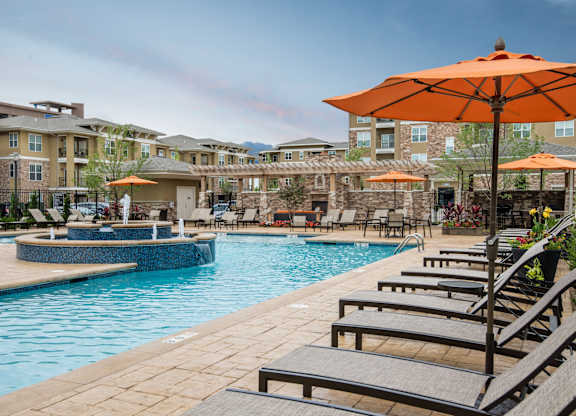 A pool area with sun loungers and umbrellas. at Residences at Prairiefire Apartment Homes, Overland Park, KS