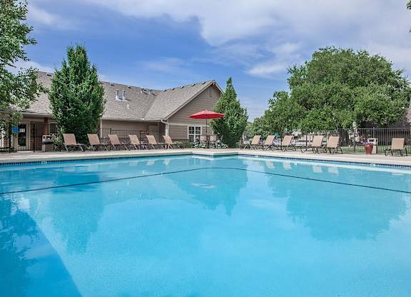 A sparkling outdoor swimming pool with landscaping and lounge chairs.