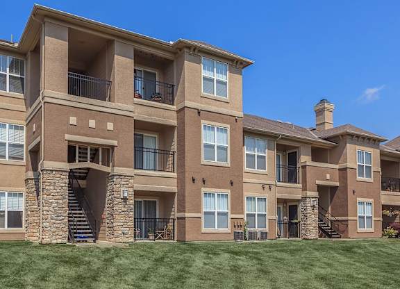 The exterior of apartment buildings overlooking a green lawn.
