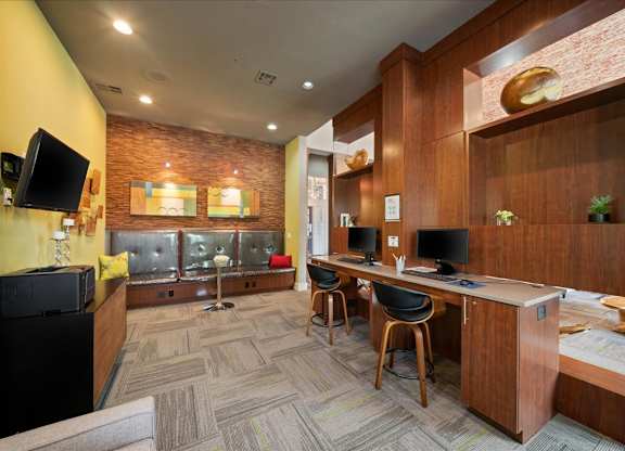A room with a brick wall and a desk with a computer.