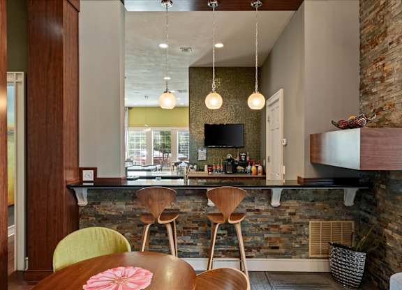 A dining area with a stone wall and wooden chairs.
