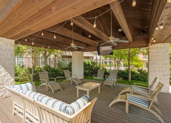 a covered patio with chairs and a tv
