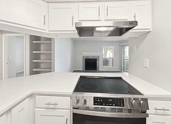 A modern kitchen with white cabinets and a stainless steel stove top.