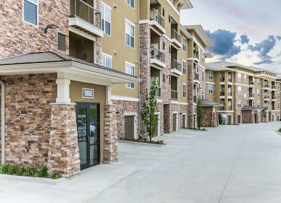 Apartment complex with a stone building and a car parked in front. at Residences at Prairiefire Apartment Homes, Overland Park, Kansas
