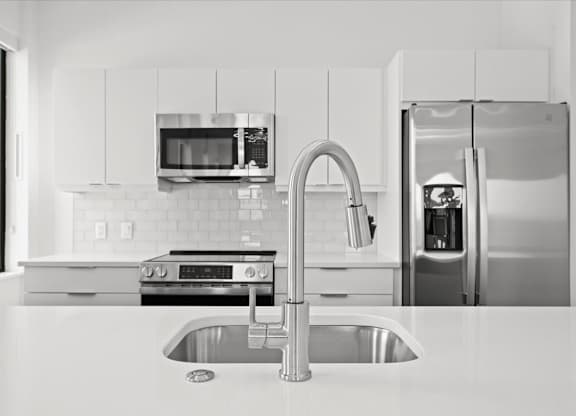 A modern kitchen with a stainless steel refrigerator and a sink.