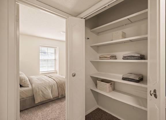 Spacious closet with built-in shelving and hanging space located next to a bedroom at Louisburg Square Apartments in Overland Park, KS.