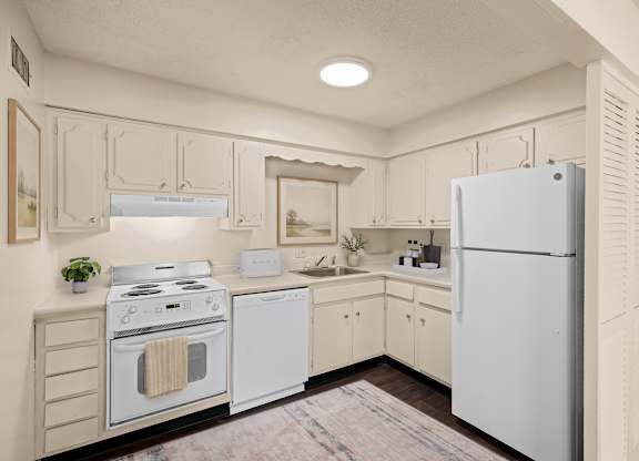 Kitchen with white cabinets, electric range, dishwasher, refrigerator, and laminate countertops at Louisburg Square Apartments in Overland Park, KS.