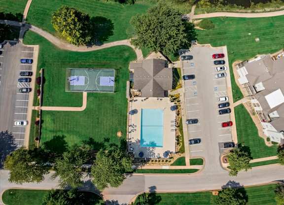 Overhead drone image of the swimming pool, basketball court, clubhouse, and surrounding apartment homes at Millcreek Woods.