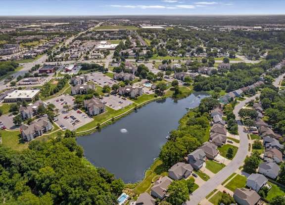 Aerial view of Millcreek Woods Apartment Homes overlooking the community lake, fountain, walking paths, and mature trees.