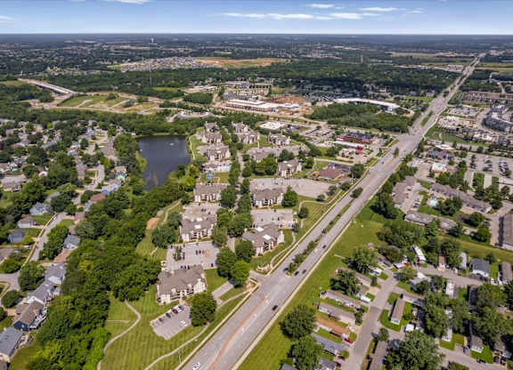 Wide drone photograph of Millcreek Woods Apartment Homes highlighting residential buildings, community amenities, and lake views.