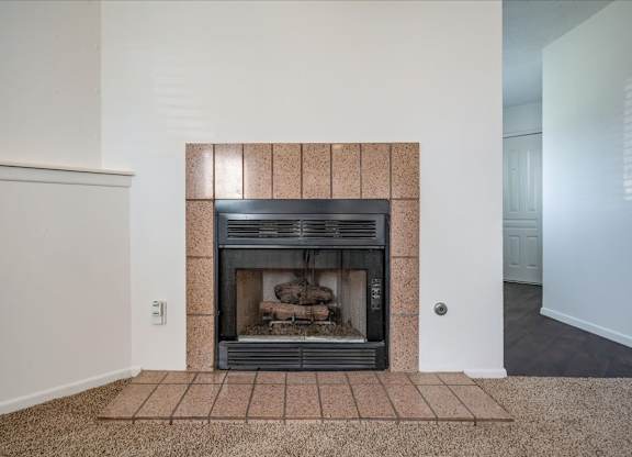 Tile-surround fireplace in a Millcreek Woods apartment home living area.