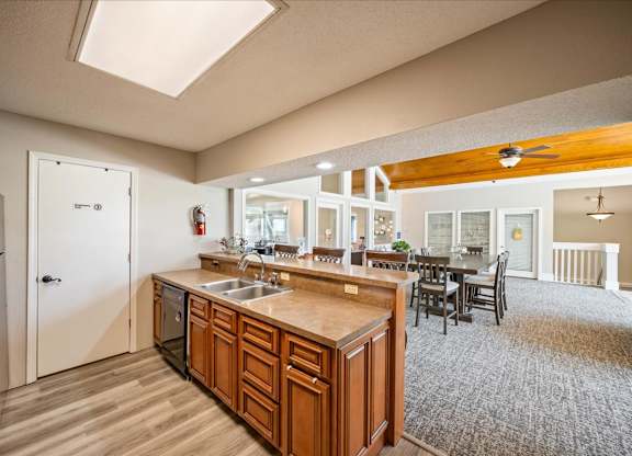 Open clubhouse kitchen with ample counter space and adjacent resident gathering area.